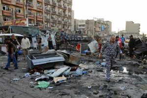 Residents look at wreckage at the site of a car bomb attack in Baghdad, Iraq